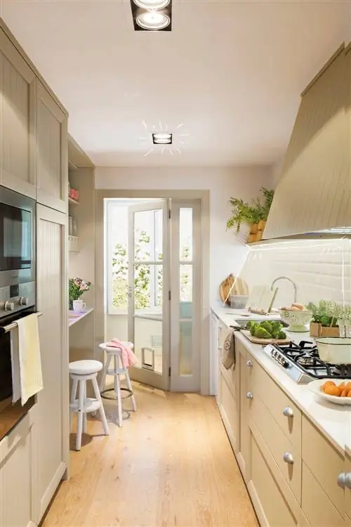 Бежевая кухня с параллельной мебелью и деревянными полами.