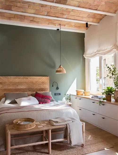 Современная спальня с зеленой стеной изголовья и жалюзи.