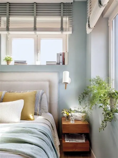 Спальня с мягким изголовьем и деревянной тумбочкой.