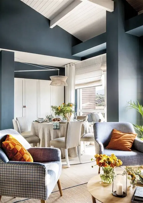 Гостиная открыта в небольшую столовую с окрашенными в синий цвет стенами.