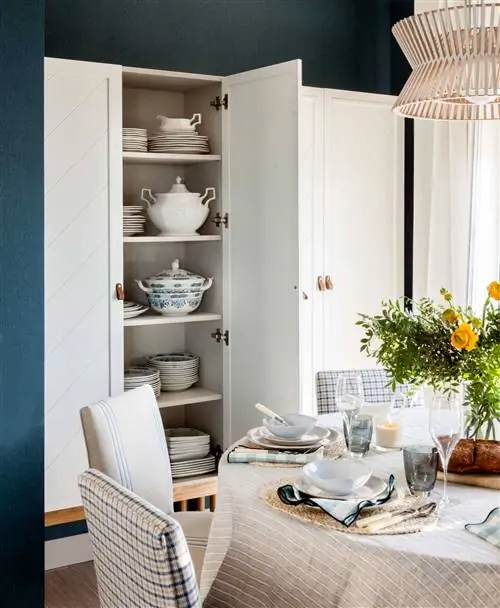 Небольшая столовая с круглым столом и открытым шкафом.