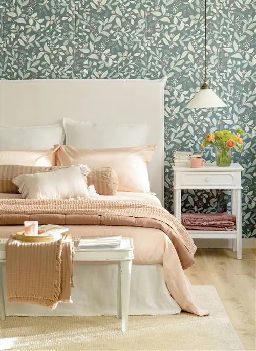 Спальня с белым льняным изголовьем и обоями с растительным рисунком.