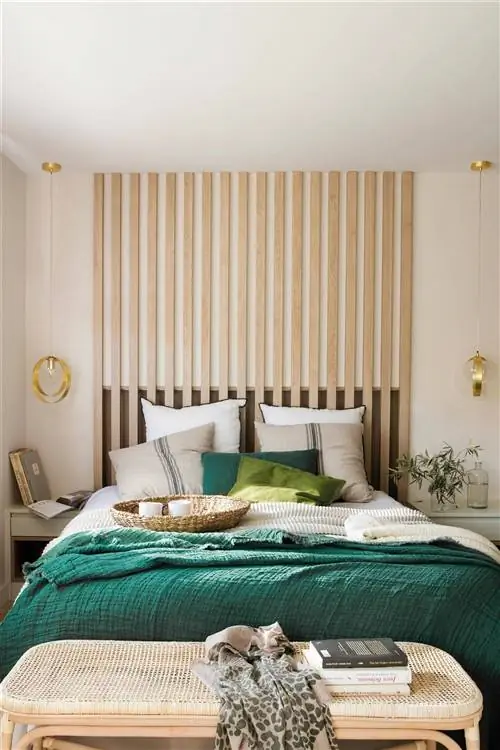 Спальня с реечным изголовьем и скамьей из дерева и ротанга.