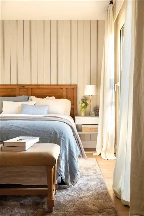Спальня с реставрированной деревянной дверью в качестве изголовья и полосатыми обоями.