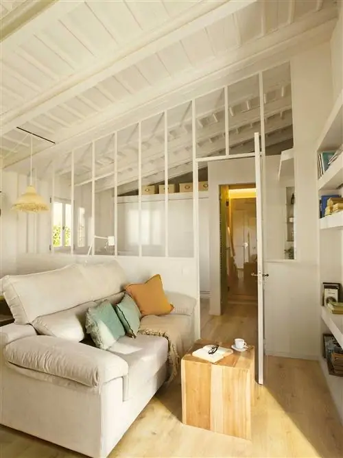 Гостиная в стиле лофт со стеклянной стеной, разделяющей гостиную и спальню.