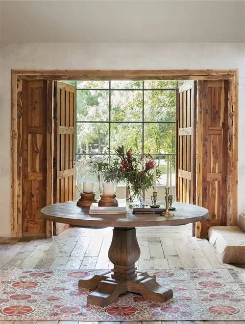 Уютный зал украшен круглым деревянным столом и классическим ковром.