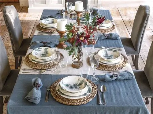 Столовая с синей льняной скатертью, узорчатой посудой, бежевыми дорожками и обитыми шипами стульями.