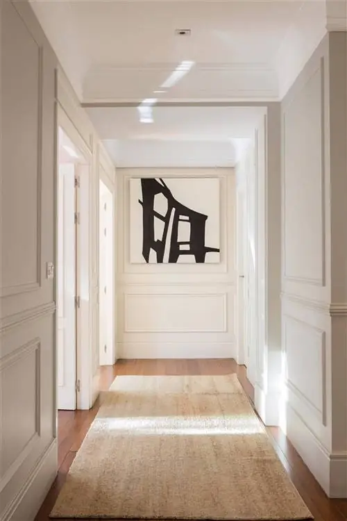 Коридор украшен белой лепниной и картиной на заднем плане.