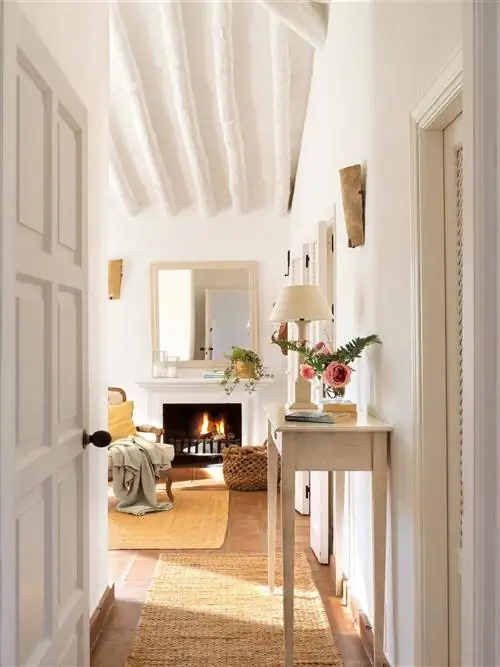 Прихожая с белой консольной настольной лампой и камином на заднем плане.