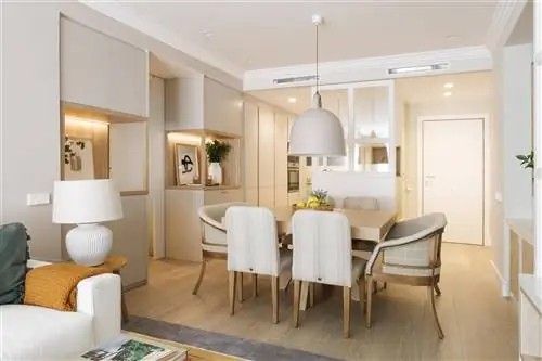 Столовая с деревянным столом, мягкими стульями и кухня со стеклянным ограждением по проекту Pia Capdevila.