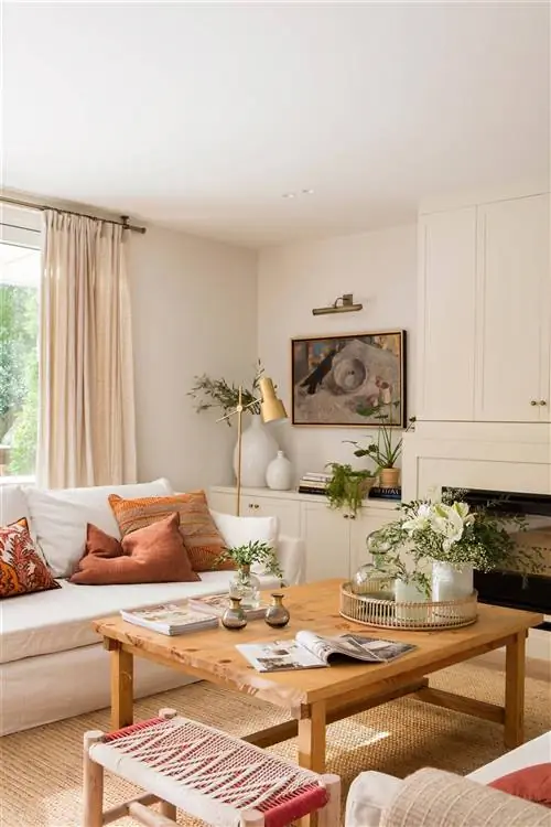 Гостиная украшена белым диваном и деревянным журнальным столиком