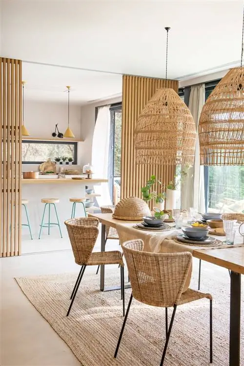 Столовая с прямоугольным дубовым столом и стульями из ротанга с изогнутыми спинками.