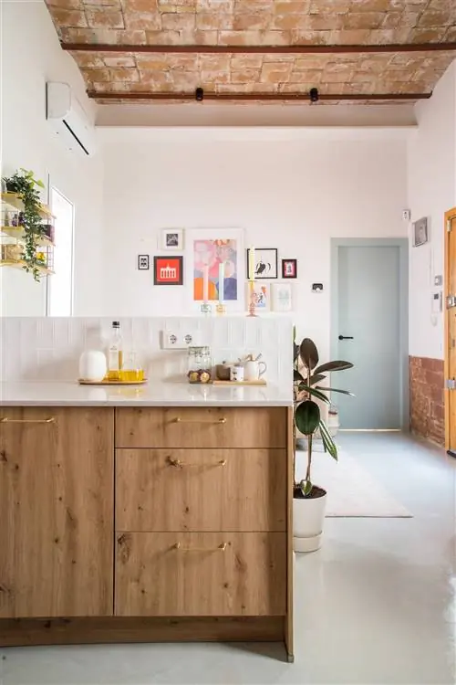 Кухня открыта для гостиной, оформленной в молодежном стиле, с открытым кирпичным потолком и стенами.