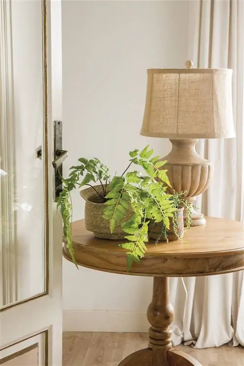 Настольная лампа на тумбочке. Имеет точеную ножку и тканевый абажур.