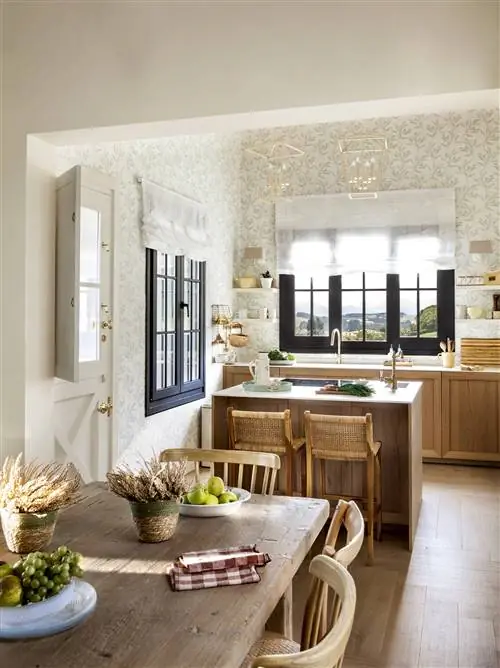 Деревенская кухня с барной стойкой, двумя табуретками и столовой с деревянным столом.