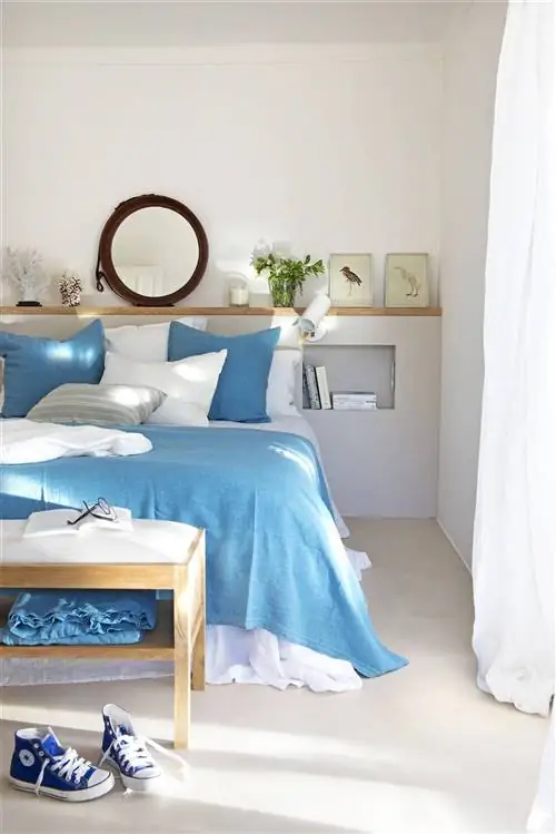 Стену изголовья украшает круглое зеркало.