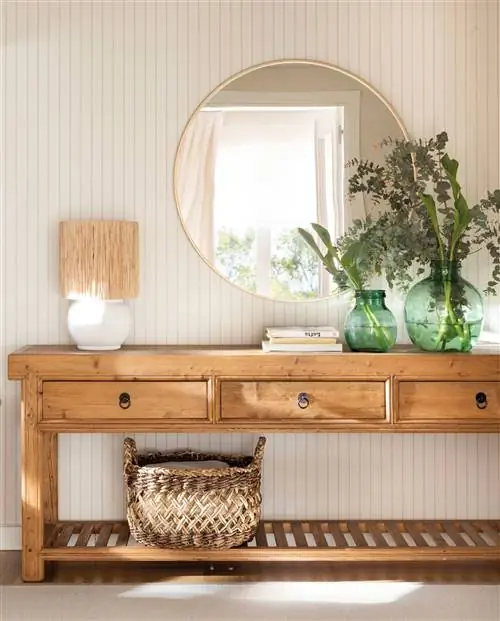 Холл с деревянной консолью и круглым зеркалом в металлической раме.