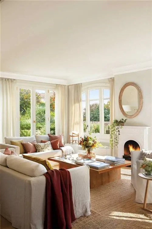 Стена камина украшена круглым зеркалом.