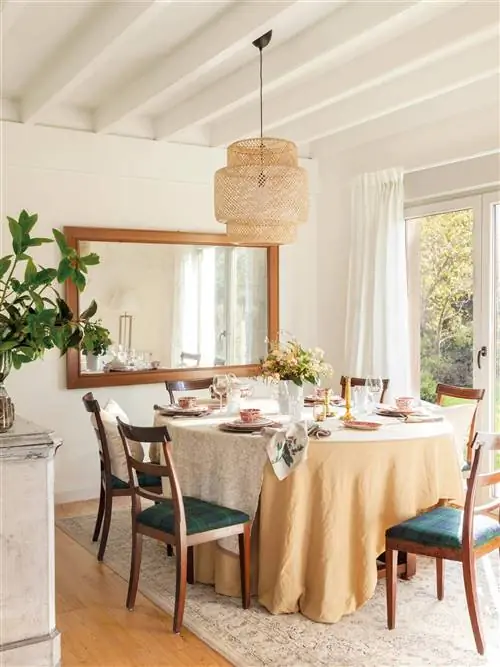 Столовая с круглым столом и большим зеркалом на стене.