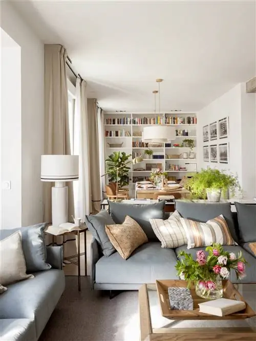 Гостиная с синим диваном и обеденной зоной позади.