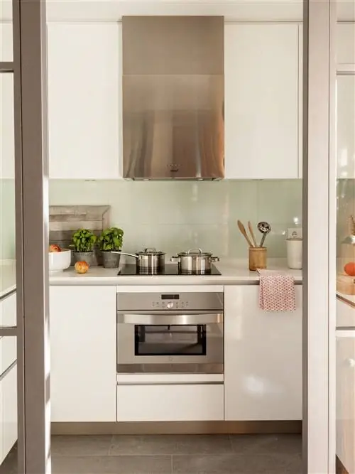 Современная кухня с белыми шкафами и техникой из нержавеющей стали.