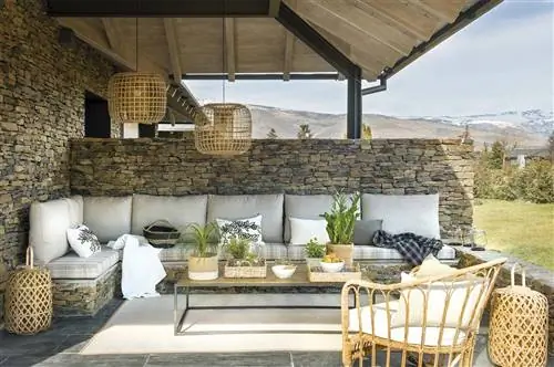 Каменная веранда с белым диваном на открытом воздухе.