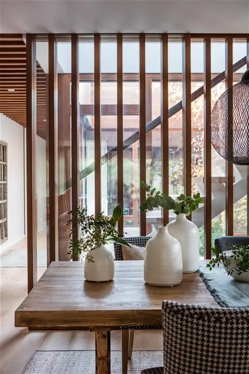 Семейство белых керамических ваз с узким горлышком, украшающих обеденный стол.