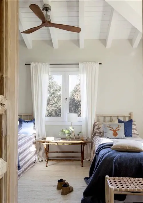 Небольшая детская комната с двумя пристроенными к стене кроватями с окном посередине