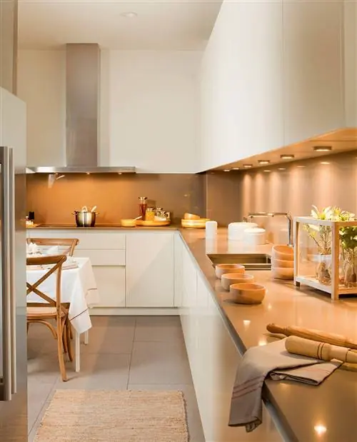 Кухня с точечными светильниками под высокими шкафами.