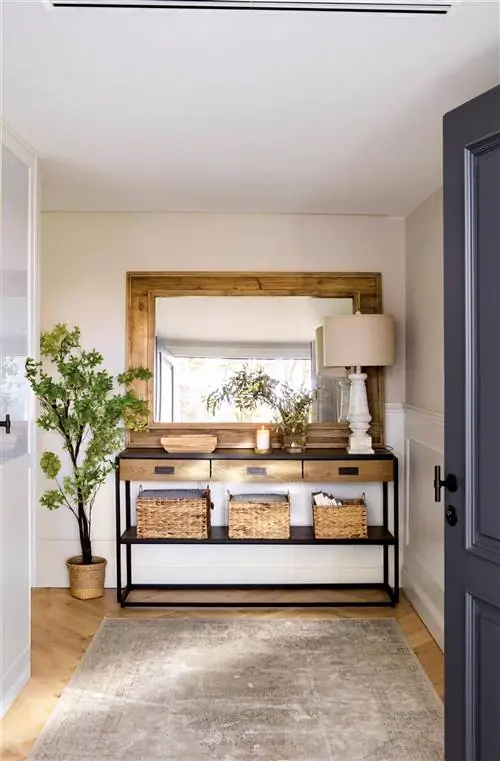 Зал с консолью и деревянным зеркалом, ковром и растением.