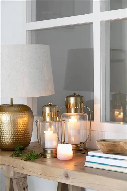 Деталь настольной лампы, фонарей и свечей на консоли зала.