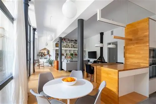 Первый этаж после реформы с белой и деревянной кухней и офисом с очень функциональным круглым и белым столом.