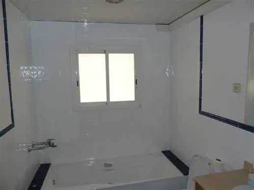 Ванная комната до ремонта с белой плиткой и панелями, ванна.