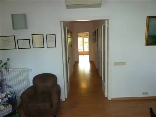 Темный коридор до ремонта, с деревянными полами и состаренной отделкой.