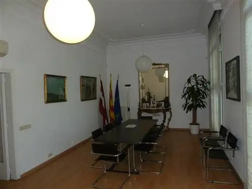 Столовая до ремонта с деревянным полом, темным столом и старыми картинами.