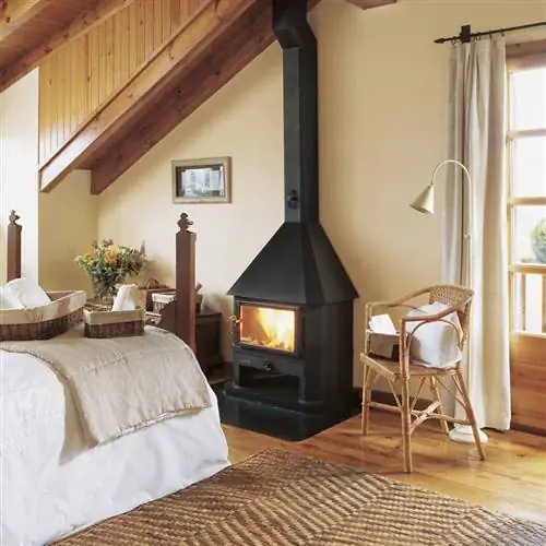 Спальня с деревянным наклонным потолком, паркетным полом, печью или камином и ковром из натурального волокна_151014