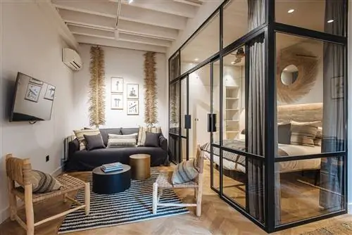 гостиная, отделанная деревом и натуральными волокнами, рядом со спальней со стеклянным ограждением с металлическими профилями