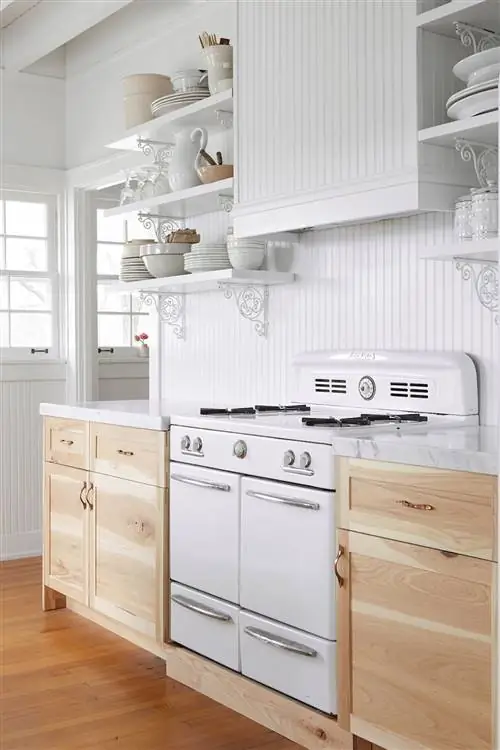 Шикарная кухня в деревенском стиле, оформленная в белых тонах, с деревянными шкафами и мраморной столешницей