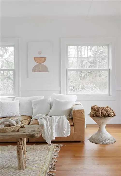 Шикарная гостиная в фермерском доме с диваном из верблюжьей кожи и журнальным столиком из необработанного дерева