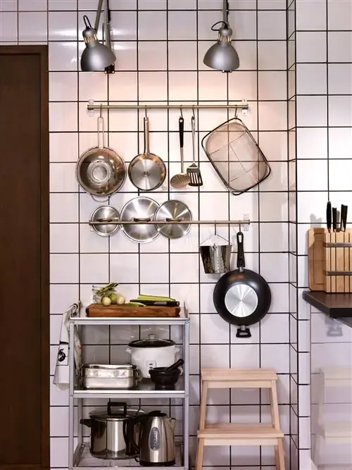 кастрюли и сковородки на подставке на кухне