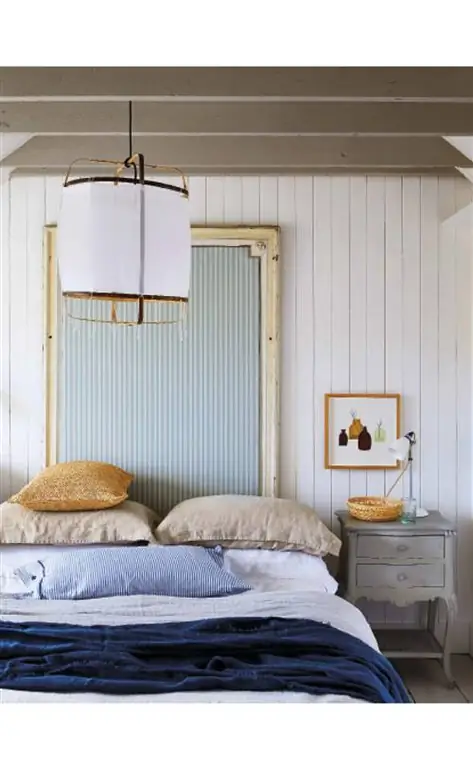 спальня с деревянными стенами и полосатым изголовьем