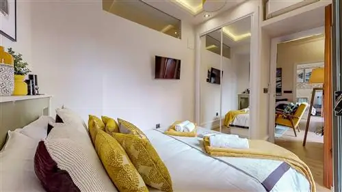 спальня с зеленым изголовьем и шкафом с зеркальными дверцами