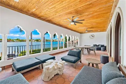 терраса в колониальном стиле с серыми диванами и креслами и деревянным реечным потолком