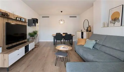 столовая с серым диваном, встроенными столами, деревянным обеденным столом и черными стульями