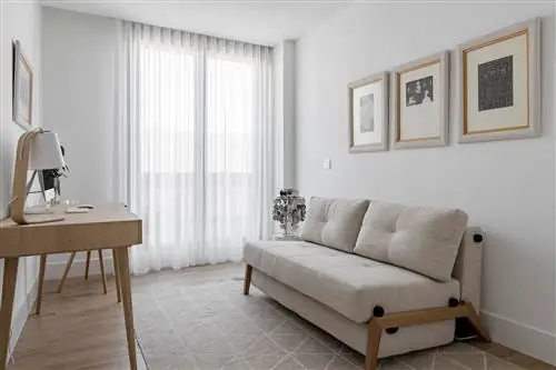 кабинет с деревянным столом и бежевым диваном-кроватью