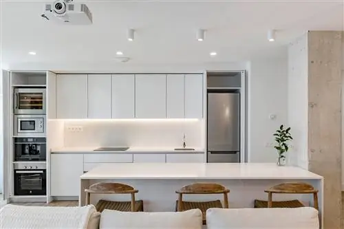 кухня в белом цвете с мраморным центральным островом рядом с цементной перегородкой