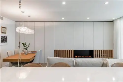 гостиная, открытая для столовой в современном дизайне, оформленная в белых тонах, с камином