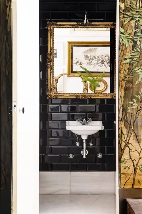 ванная комната с черной плиткой метро и золотым зеркалом