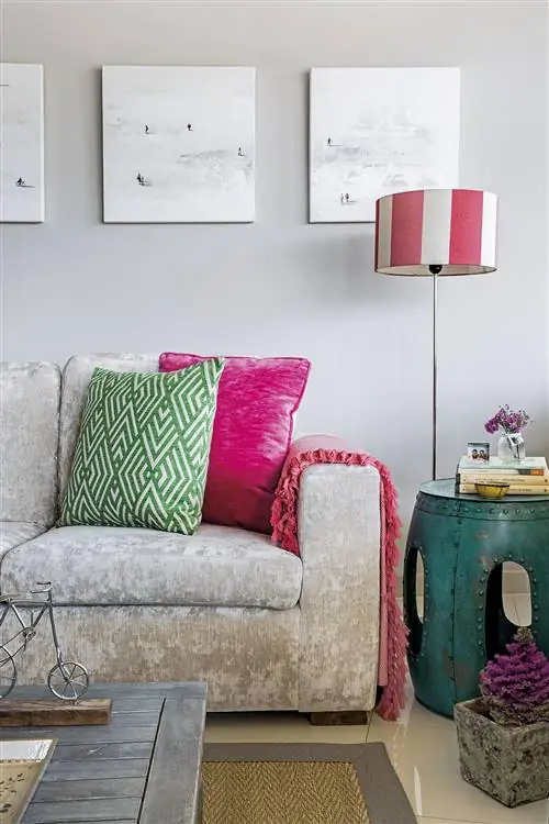 серый диван для гостиной с зелеными и розовыми подушками