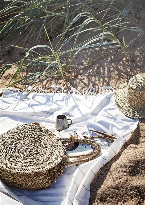 круглая соломенная сумка и полотенце на пляже